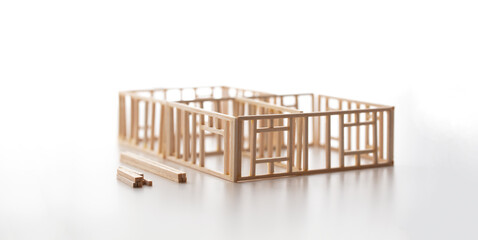 Building a house or a home. Frame work of a house (miniature model) isolated on neutral white with natural shadows.