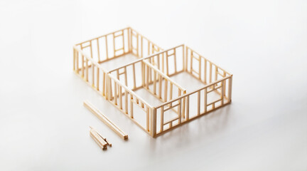 Building a house or a home. Frame work of a house (miniature model) isolated on neutral white with natural shadows.