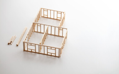 Building a house or a home. Frame work of a house (miniature model) isolated on neutral white with natural shadows.