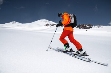A skier in an orange suit skis in a mountain off-piste skiing in the northern caucasus of Mount...