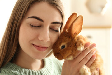 Young woman with adorable rabbit indoors, closeup. Lovely pet