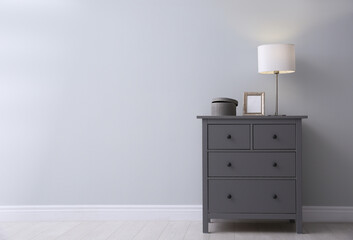 Modern grey chest of drawers near light wall in room, space for text. Interior design