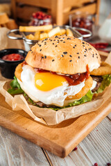 Appetizing burger with fried egg on wooden board