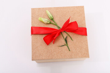 Small wooden box with red bow and flower petals on top. Gift box isolated on a white background