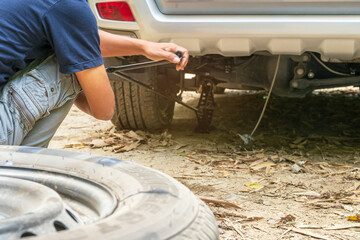 Man changing wheel after a car breakdown on the street in nature.