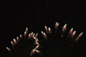 Fireworks of a festive evening at night, shimmers from a silver glow to a golden one.