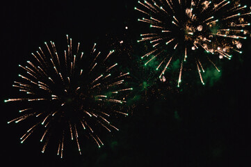 Pyrotechnic composition of a golden glow in the sky against a background of emerald haze from previous volleys.