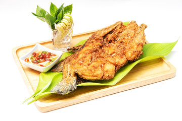 Deep fried sea bass with fish sauce and green mango chili fish sauce, based on chili fish sauce, addition of shredded green mango and lime juice serving on wooden tray isolated on white background.