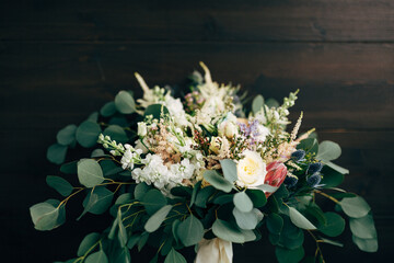 Obraz na płótnie Canvas bridal bouquet of white and cream roses, branches of eucalyptus tree, protea, eryngium, delphinium and white ribbons