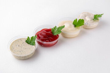 Assorted different sauces in plastic: ketchup, mustard, sour cream. Topping for dishes for delivery. Isolated on a white background.
