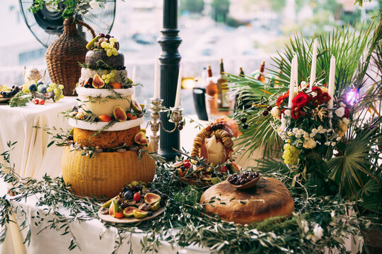 The buffet table at the festival is a makeshift cheese cake. The table is decorated with olive branches and leaves.