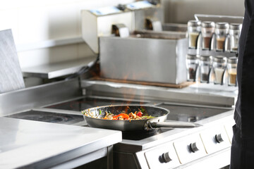 Cooking tasty food on stove in restaurant kitchen