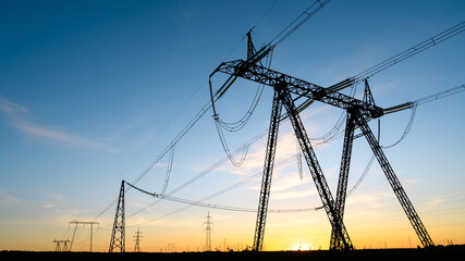 Silhouettes of High voltage pylons at sunset. High voltage power lines in the evening sky. Copy...