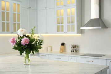 Peony bouquet on white marble table in kitchen interior