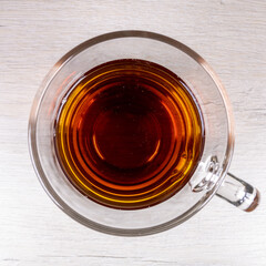Glass transparent cup with black tea with a top view.