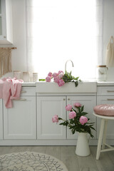 Beautiful pink peonies in stylish kitchen interior