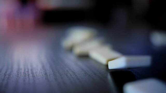Domino slowly falling on a wooden table shot in slow motion at 180fps
