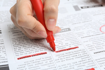 Obraz premium Woman marking advertisement in newspaper, closeup. Job search concept