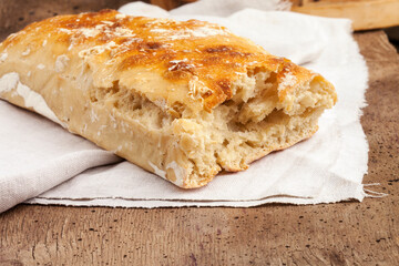 Ciabatta. Fresh italian ciabatta bread with herbs, olive oil and olives on a wooden background, top view