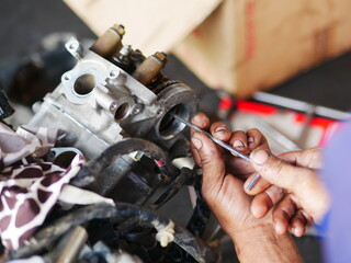 Mechanic working on motorcycle engine in workshop. 
