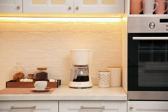 Modern coffeemaker on countertop near brick wall in kitchen