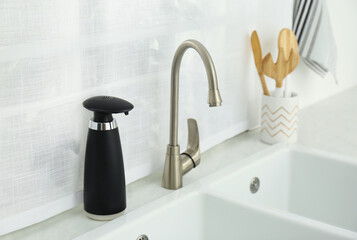 Modern automatic soap dispenser near sink in kitchen