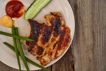 Ready pork steak in a white plate with green onions on an old wooden table. With copy space.