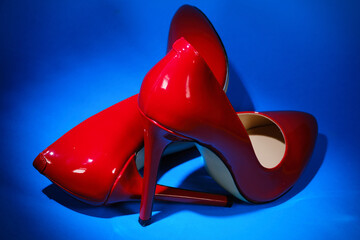 patent leather shiny female red stilettos on a blue background