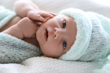 Obraz na płótnie Canvas Cute newborn baby in warm hat lying on white plaid, closeup