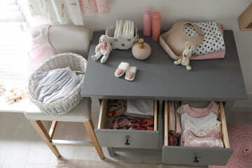 Open cabinet drawers with baby shoes and clothes in child room