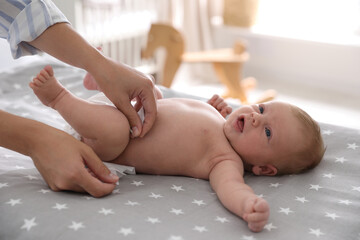 Mother changing her baby's diaper on bed