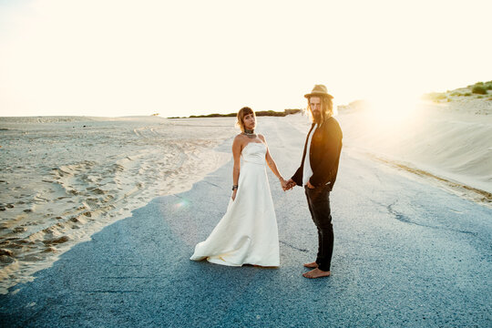 A trendy an attractive caucasian blonde couple in a beach weeding in the sunset time
