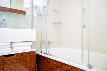 Clean and modern design bathroom with sink, shower, bath tub, towels and mirror and mosaic tiles in...