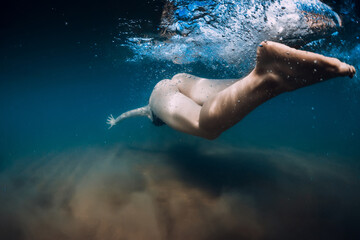Fototapeta na wymiar Woman dive without surfboard under wave. Underwater duck dive under wave and sandy bottom