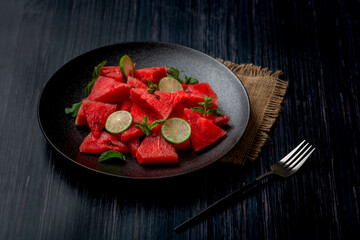 fresh watermelon salad kept in a black plate on dark background
