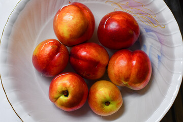 White ceramic bowl full of fresh peaches in water