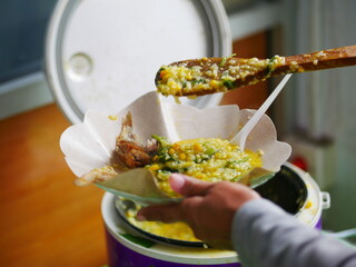 Person taking Menado porridge with wood spoon and takes a spoonful. Menado porridge for breakfast. Indonesian traditional food.