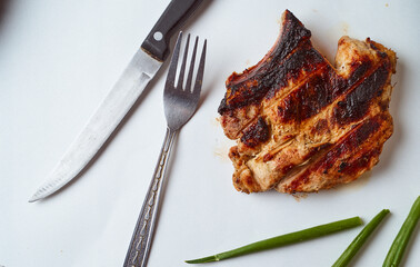Ready pork steak in a white plate with green onions on a white plate. With copy space.