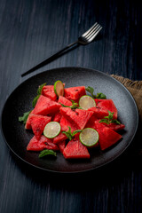 fresh watermelon salad kept in a black plate on dark background
