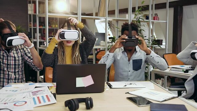 Close up of attractive satisfied creative international workteam which working in virtual reality headset in contemporary office
