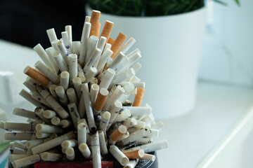 Pile of smoked used cigarettes in an ashtray. Mountain of cigarettes and  copy space