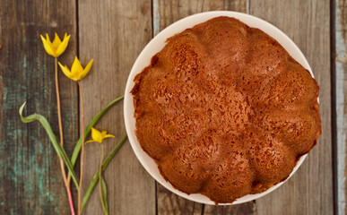 Homemade cupcake with chocolate filling inside on a wooden table with a Yellow Woodland tulips, Wild tulips on a wooden background. Top view.