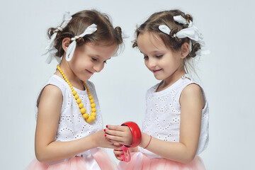 two little girls play with their mother's makeup. they pose and try to be adults.Studio, white...