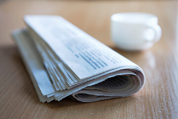 Fototapeta premium Folded newspaper on a wooden table with coffee