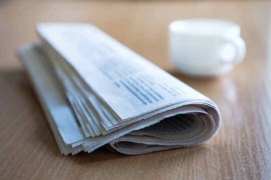 Folded Newspaper On A Wooden Table With Coffee