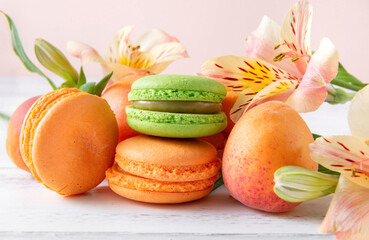 peach, green macaroon cookies, fresh apricots,  yellow Alstroemeria flowers  on a beige