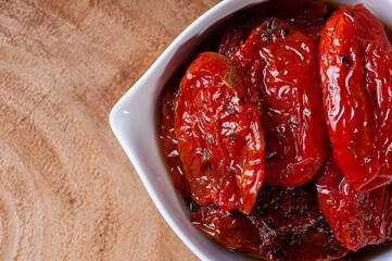 .Sun-dried tomatoes in a white bowl on a woody background. Top view