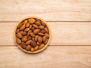 Top view almonds in wood plate on pine wood table with copy space.