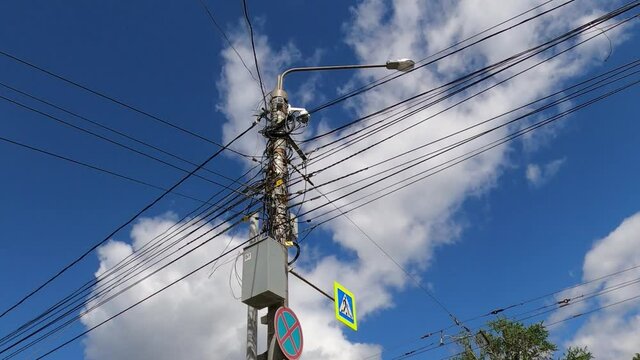 A lot of wires against the blue sky with moving clouds.