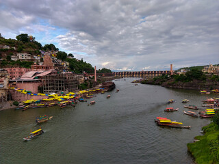 Famous Omkareshwar Jyotirling temple, Omkareshwar dam and holy Narmada river all are in one frame. Colorful boats are floating in the river.
